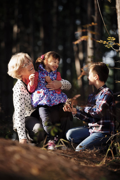 Isoäiti, lapsenlapsi ja lapsenlapsi leikkivät metsässä. Generaation käsite
 - Valokuva, kuva