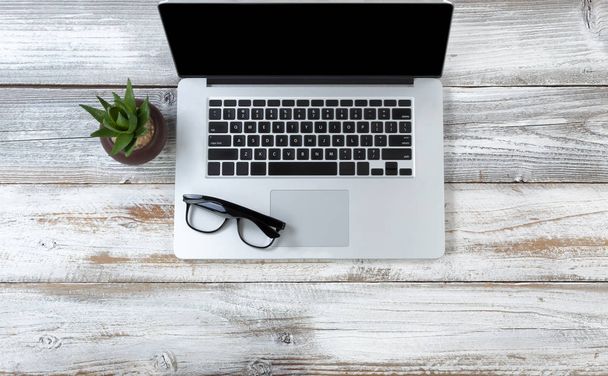 Bovenaanzicht van een laptop met Leesbrillen op witte roest - Foto, afbeelding