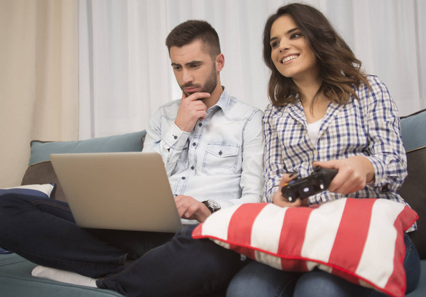 Frau spielt zu Hause Videospiele, während Mann am Laptop arbeitet - Foto, Bild