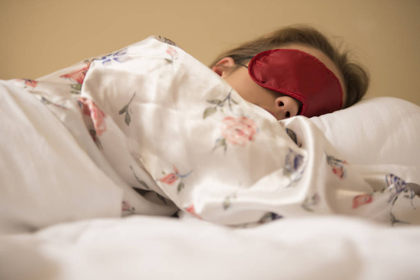 Zmęczony kobiecie spania w łóżku nosić opaskę snu maska - Zdjęcie, obraz