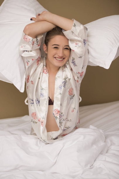 Pelea de almohadas con una mujer feliz y sonriente
 - Foto, Imagen