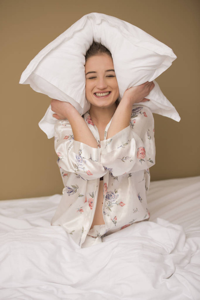 Pillow fight with a happy smiling woman - 写真・画像