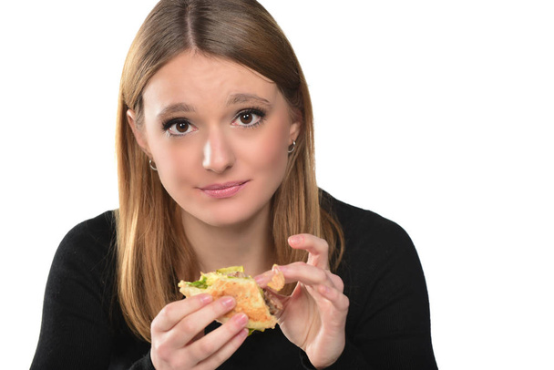 retrato de uma bela menina comendo um hambúrguer no fundo branco
 - Foto, Imagem