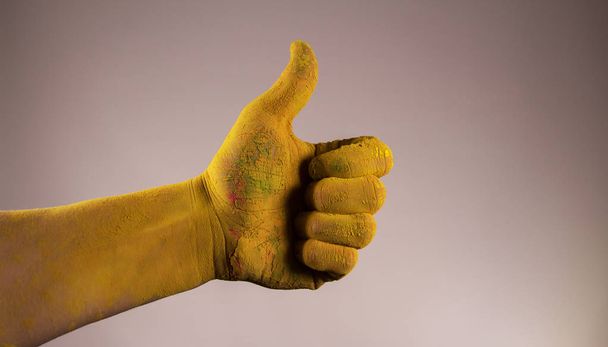 Pollice a mano in alto macchiato di vernice gialla holi
 - Foto, immagini