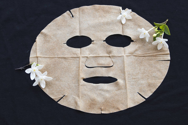 máscara de hoja natural marrón para la cara de la piel de la flor de hierbas en el fondo negro
 - Foto, imagen