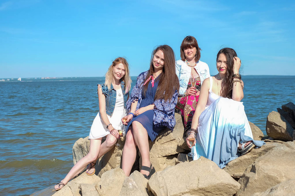 концепція літніх канікул - група усміхнених молодих жінок відпочиває на узбережжі
 - Фото, зображення