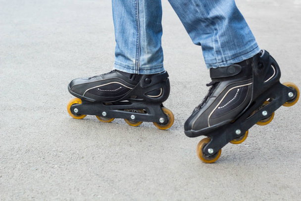 Young man in blue jeans riding roller skates in the city. Close up legs - Photo, Image
