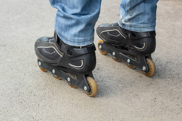 Young man in blue jeans riding roller skates in the city. Close up legs - Zdjęcie, obraz