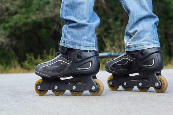 Young man in blue jeans riding roller skates in the city. Close up legs - Photo, Image