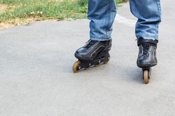 Young man in blue jeans riding roller skates in the city. Close up legs - Фото, зображення