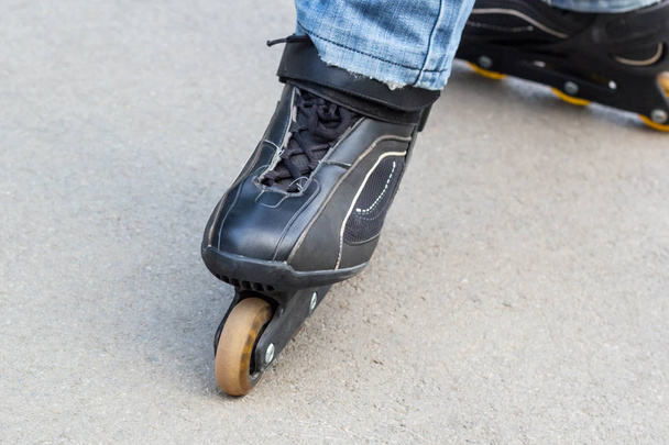 Young man in blue jeans riding roller skates in the city. Close up legs - Foto, imagen