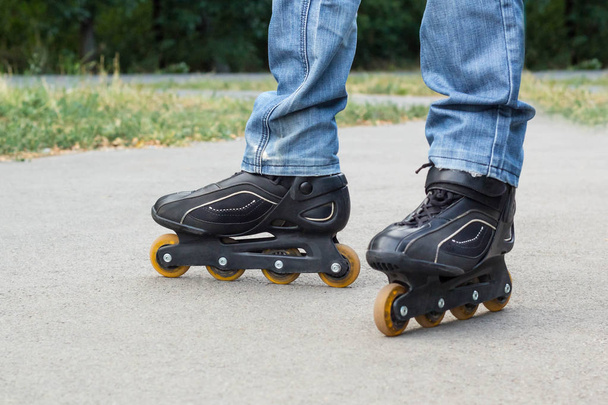 Young man in blue jeans riding roller skates in the city. Close up legs - Foto, Imagem