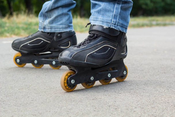 Young man in blue jeans riding roller skates in the city. Close up legs - Photo, image