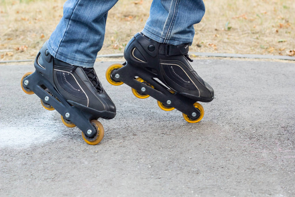 Young man in blue jeans riding roller skates in the city. Close up legs - 写真・画像