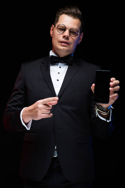 近代的なスマート フォンを保持しているスーツを着た若いハンサムな男  - 写真・画像