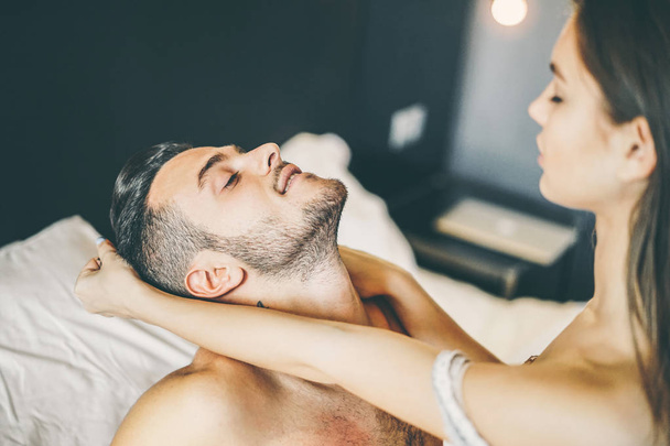 Молодая страстная пара, занимающаяся сексом на кровати дома - Чувственная девушка дергает своего парня за волосы - Концепция ролевой игры в интимные любовники в спальне - Сосредоточьтесь на мужском лице
 - Фото, изображение