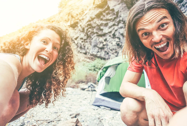Felice coppia amorevole di escursionisti campeggio e fare un selfie utilizzando la fotocamera dello smartphone cellulare - Giovani godendo tenda campo prendere un autoritratto con smartphone - Concetto di stile di vita di relazione
 - Foto, immagini