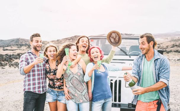 Grupo de amigos felizes fazendo festa no deserto - Viajar pessoas se divertindo bebendo champanhe prosecco durante sua viagem de carro de jipe - Amizade, férias, conceito de estilo de vida feriado
 - Foto, Imagem