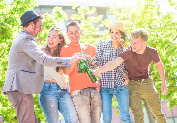 屋外 - 都市 - 青年友好パーティ コンセプト - ビールのボトルを焼くこと左の男に焦点を当てる腕を一緒に楽しんで幸せな若者のビールを楽しんでいる友人のグループ - 写真・画像