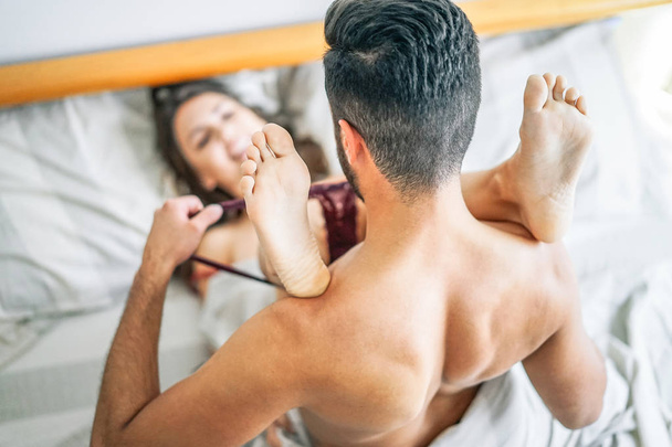 Uomo spogliare lingerie del suo partner - Fidanzato rimandare le mutandine della sua ragazza prima di fare sesso sul letto - Momenti sexy e intimi della coppia - Appassionato, sessuale, concetto di amore
 - Foto, immagini