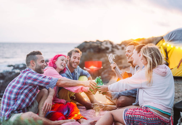 Grupo de amigos animando con cervezas al aire libre - Gente feliz acampando con tienda y haciendo una barbacoa divirtiéndose brindando botellas de cerveza - Amistad, estilo de vida, concepto de campamento
 - Foto, imagen