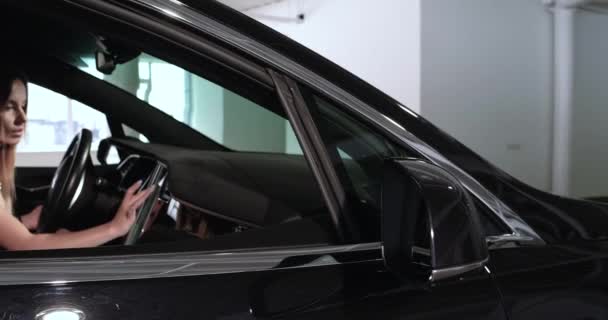 Young woman sits behind steering wheel in Tesla car - Кадри, відео