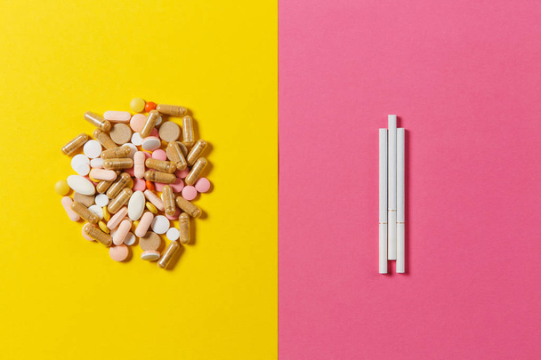 Het kleurrijke ronde tabletten medicatie witte geregeld abstract drie sigaretten op gele kleur achtergrond. Capsule pillen voor design. Behandeling, keuze gezonde levensstijl concept. Ruimte reclame kopiëren. - Foto, afbeelding