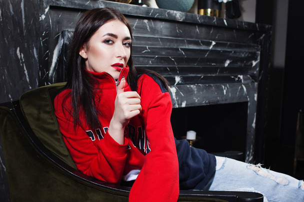 Trendy young woman ia a red hoodies. Portrait in fashionable interior. - Photo, Image
