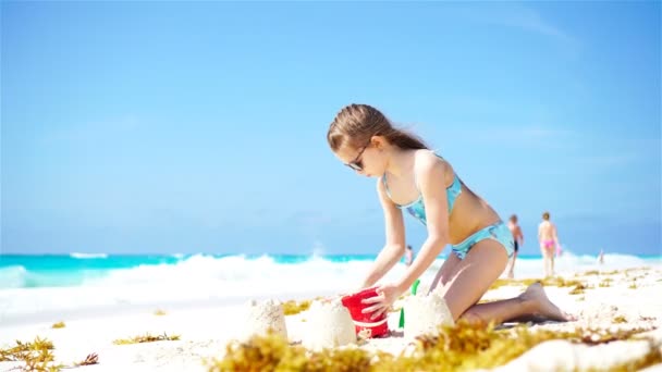 Schattig meisje spelen met speelgoed en zandkasteel op strandvakantie - Video