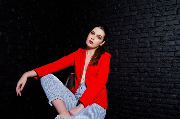 Stylish brunette girl on red jacket against studio black brick w - Fotoğraf, Görsel