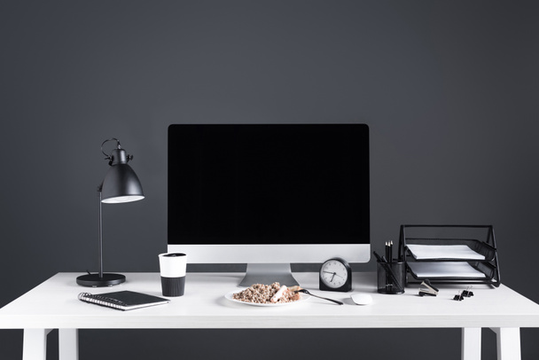 computadora de escritorio con pantalla en blanco, comida en la placa y suministros de oficina en el lugar de trabajo
 - Foto, Imagen