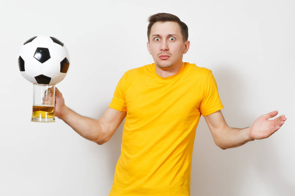 Inspired young fun shocked European man, fan or player in yellow uniform hold pint mug of beer, soccer ball cheer favorite football team isolated on white background. Sport, play, lifestyle concept. - Foto, immagini