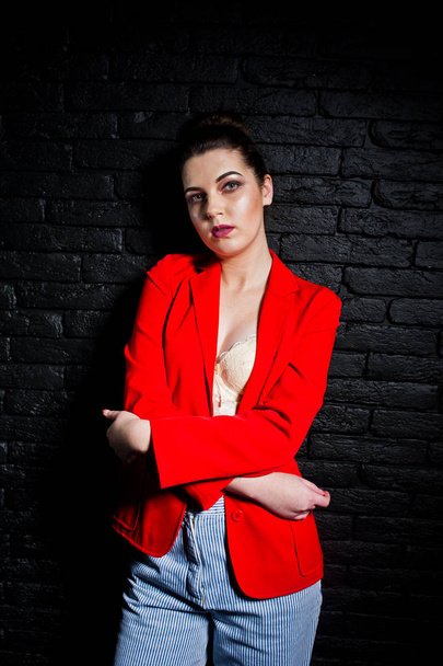 Stylish brunette girl on red jacket against studio black brick w - Foto, imagen