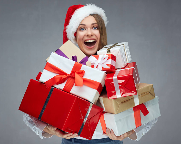 businesswoman wearing Santa hat holding pile of christmas gifts - Fotoğraf, Görsel