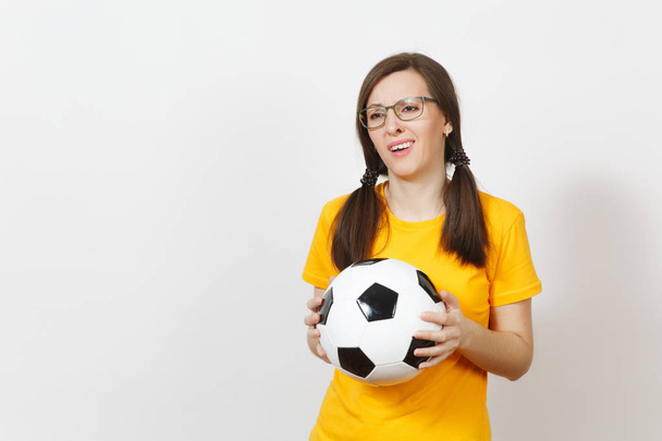 Evropská mladá smutný rozrušená žena, dvě zábavné pony ocasy, fotbalový fanoušek nebo hráč v brýle, žluté jednotná hold klasické fotbalový míč izolovaných na bílém pozadí. Sport, hrají, fotbal, co zdravého životního stylu - Fotografie, Obrázek