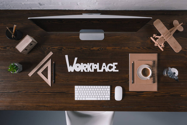 верхний вид рабочего места с настольным компьютером и офисными принадлежностями на деревянном столе
 - Фото, изображение
