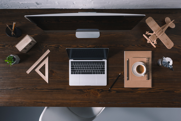 верхний вид настольного компьютера, ноутбука и офисных принадлежностей на деревянном столе
  - Фото, изображение