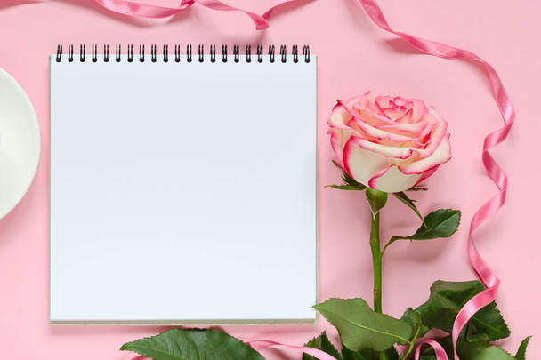 Pink blooming fresh rose flower with notebook on pink background - Zdjęcie, obraz