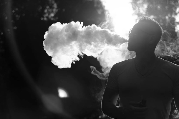 Man with beard smoke electronic cigarette outdoor, black and white - Φωτογραφία, εικόνα
