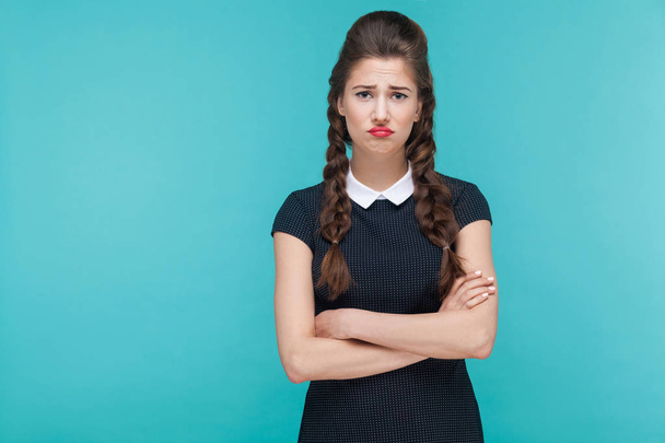 unhappy businesswoman standing with crossed arms and looking at camera with sadness on  blue background - Zdjęcie, obraz