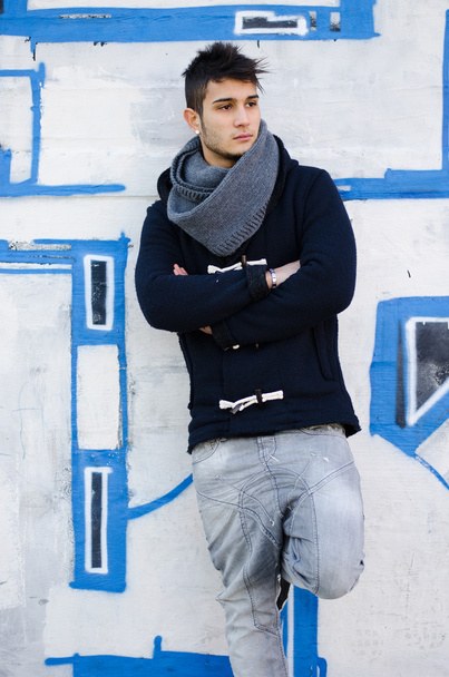 Handsome young man standing against graffiti covered wall - Zdjęcie, obraz