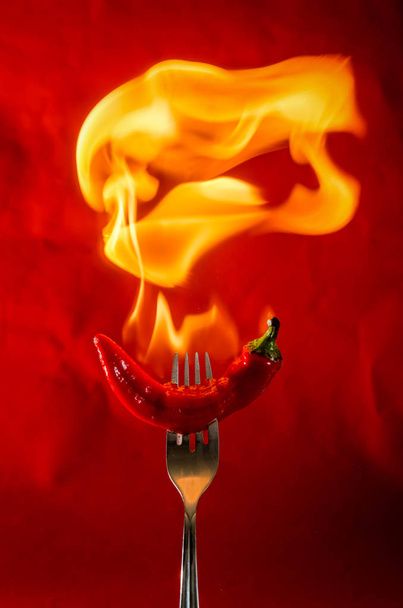 Pimienta picante roja sobre fondo negro con llama - Foto, imagen