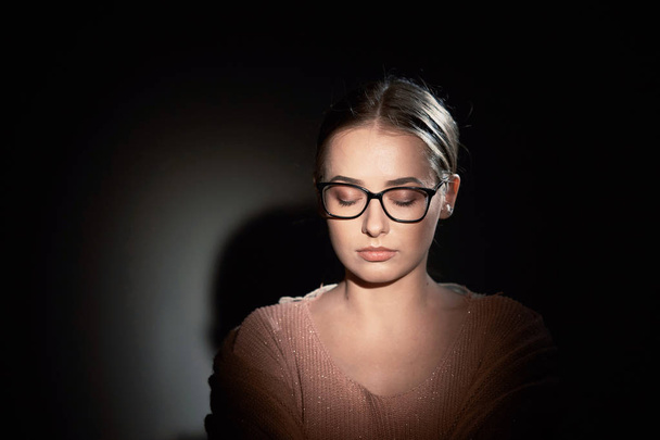 menina de óculos no estúdio em um fundo escuro. manchas de luz
. - Foto, Imagem