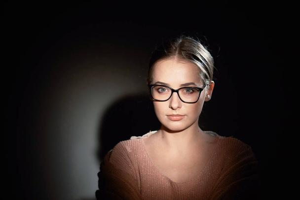 menina de óculos no estúdio em um fundo escuro. manchas de luz
. - Foto, Imagem