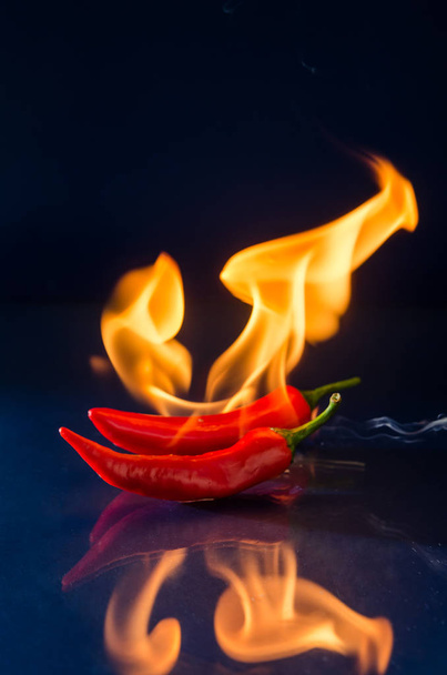 Κόκκινο καυτερό πιπέρι τσίλι σε μαύρο φόντο με φλόγα - Φωτογραφία, εικόνα