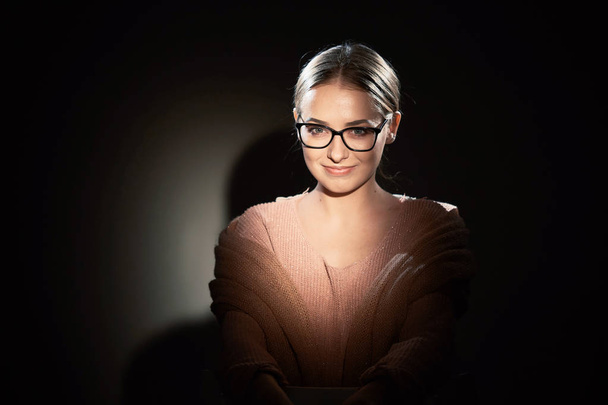 girl in glasses in studio on a dark background. light spots. - Foto, Bild