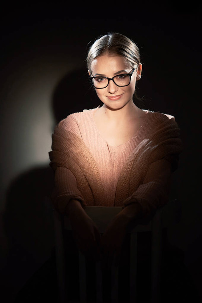 girl in glasses in studio on a dark background. light spots. - Фото, зображення