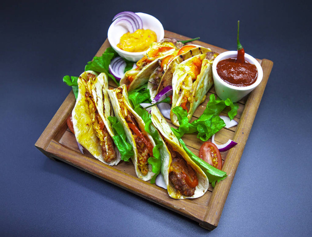Tacos und Chilisoße. mexikanische Tortillas mit einer Füllung aus heißem Fleisch. Nahaufnahme von Tacos. - Foto, Bild