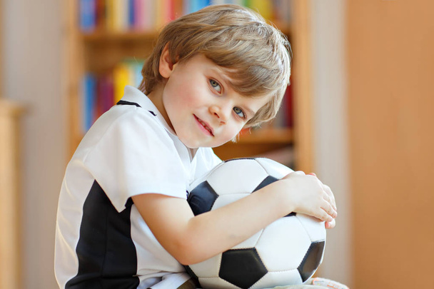 Malý blond školka kluk s míčem sledování fotbal fotbal pohár hra v televizi. - Fotografie, Obrázek