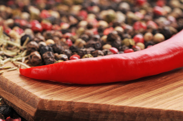Red hot pepper with peppercorns on the wooden cutting board - Foto, immagini